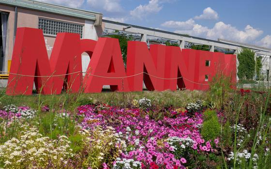 Flowers bloom in front of large letters that spell out "Mannem," the slang name for Mannheim, Germany. The building behind it was once a U.S. Army warehouse at the former Spinelli Barracks.