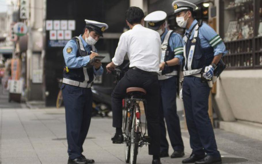 Tokyo Metropolitan Police stop a bicyclist on a street in Tokyo on Sept. 1, 2020.