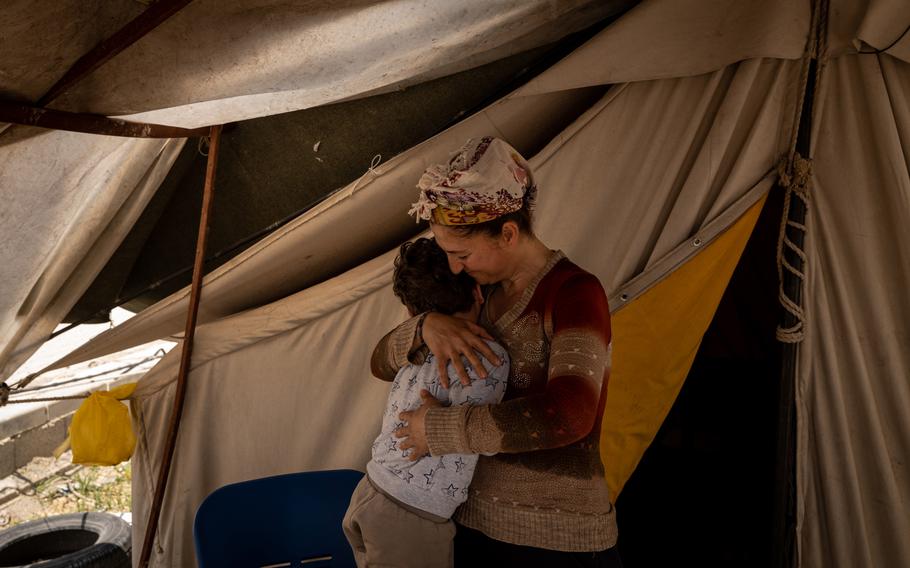 Selva Muhterem hugs her son Musa outside their tent in Samandag. 