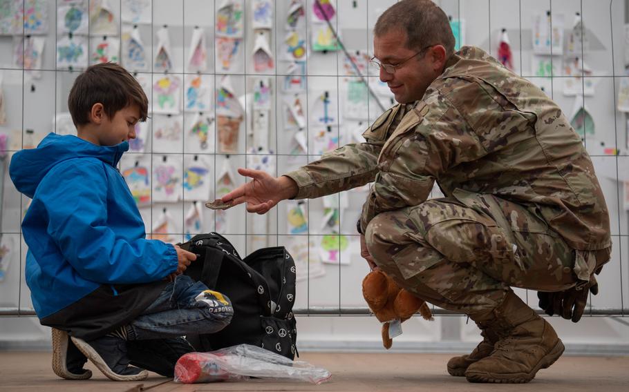 U.S. Air Force Tech. Sgt. Manuel Villarreal, 691st Cyber Operations Squadron virtual operations supervisor, offers his patch to an evacuee at Ramstein Air Base, Germany, Saturday, Oct. 9, 2021. Around 300 Afghans left Ramstein that day when flights for evacuees to the U.S. resumed after a three-week pause.