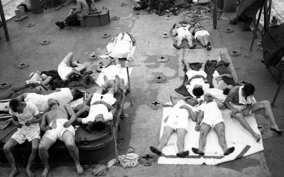 Sailors who survived the sinking of the USS Indianapolis on July 30, 1945, lie on the deck of the USS Bassett after being rescured.