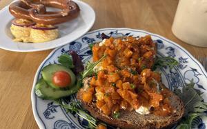 Handkäse tartar with apple chutney on roasted homemade bread, foreground, and an oven-fresh pretzel with Bavarian obatzda at Henninger am Turm in Frankfurt are good snacks to go with a beer or be ordered as a small appetizer before your main course. 