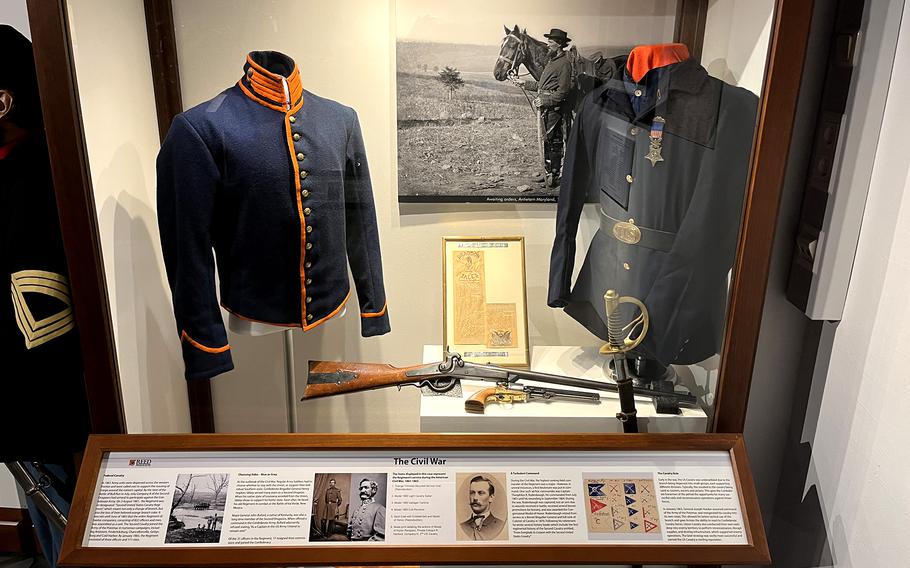 Military uniforms are on display in a museum.