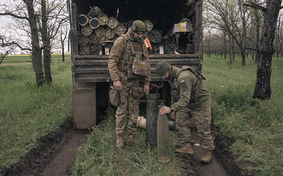 Members of the 406th Separate Artillery Brigade prepare to load a howitzer. 