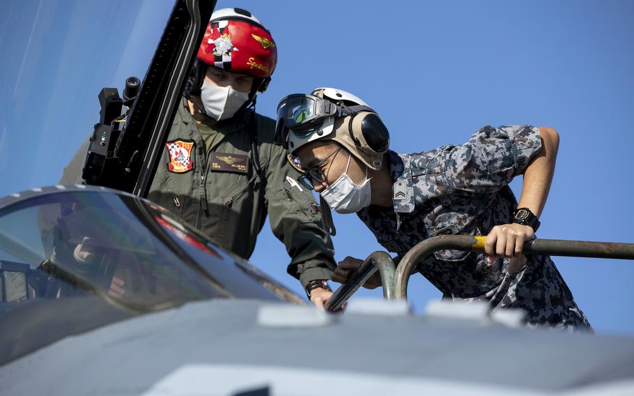 Marine Corps Capt. Reagan Reynolds, a pilot with Marine Fighter Attack Squadron 312, shows the cockpit of an F/A-18C Hornet to Japan Air Self-Defense Force Technical Sgt. Nozaki during exercise Keen Sword at Nyutabaru Air Base, Japan, Nov. 16, 2022. 