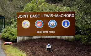 A brown entrance sign with bushes and trees behind it at Joint Base Lewis-McChord.