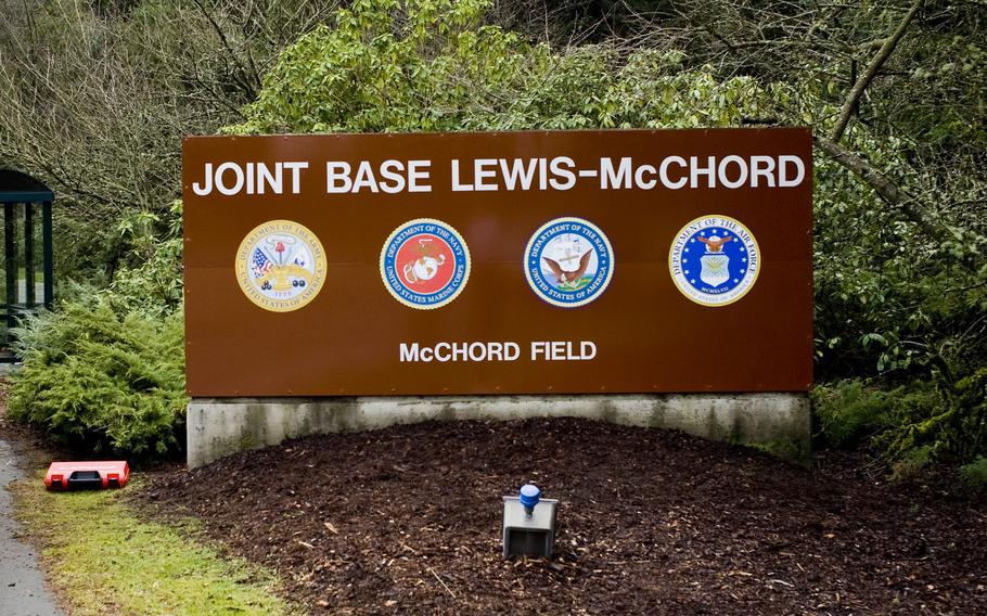 A brown entrance sign with bushes and trees behind it at Joint Base Lewis-McChord.
