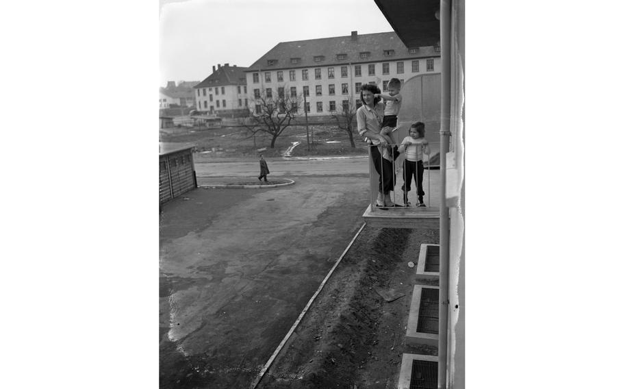 A vertical, black and white photo of a family looking out at a balcony.