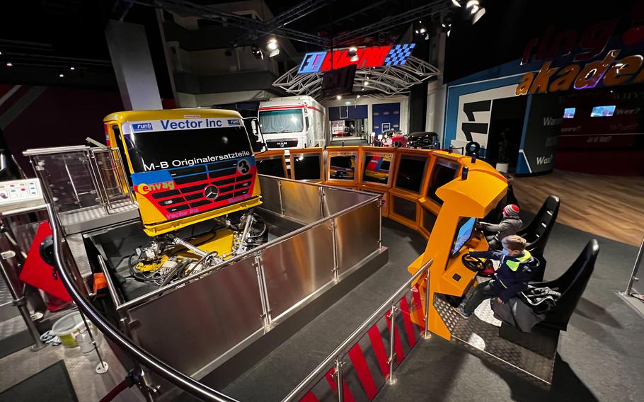 Kids play a truck racing video game in Nuerburg, Germany, Jan 15, 2022. A full-sized semitrailer truck cab simulator allows visitors to Ringwerk to experience the tilt and rumble of a racing truck as it drifts around the Nuerburgring track. Additional players can join in the same on-screen race from attached driver consoles.