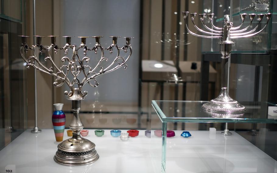 A pair of silver hanukkiahs on display at the Jewish Museum in Frankfurt. In the background is a colorful, modern interpretation of one by Avi Biran. 