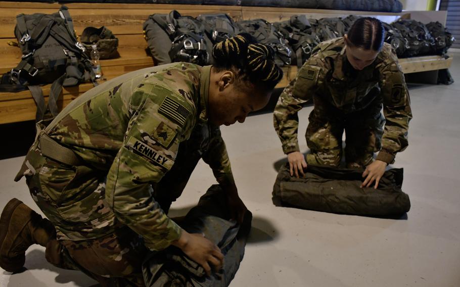 Two U.S. Army paratroopers fold their parachute retrieval bags ahead of the 173rd Airborne Brigade's all-female parachute jump near Vajont, Italy, on March 14, 2024.