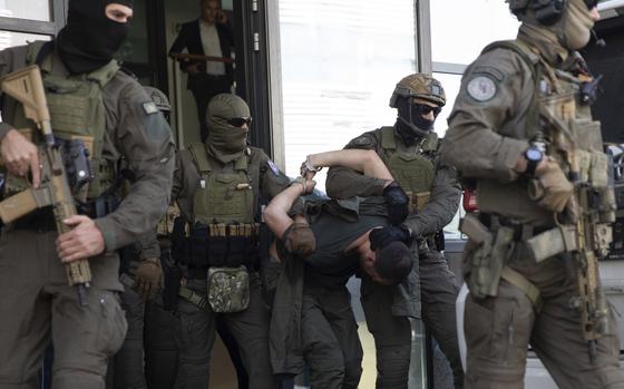 Kosovo police members of Special Intervention Unit escort one of the arrested Serb gunmen out of the court after the Kosovo shootout in capital Pristina, on Tuesday, Sept. 26, 2023. (AP Photo/Visar Kryeziu)
