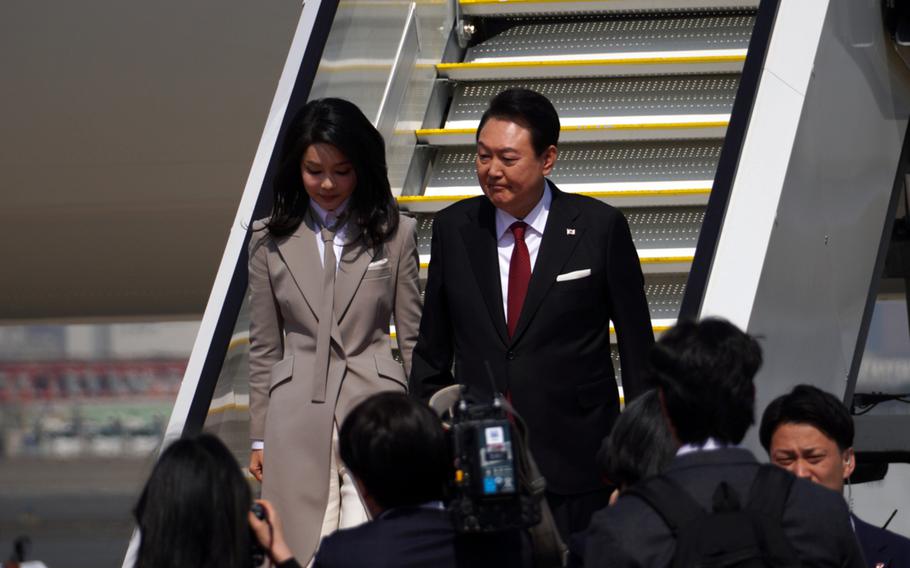  Yoon Suk Yeol and his wife walk down stairs as they depart an airplane.