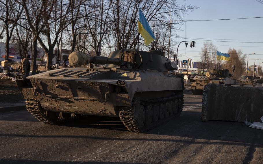 Tanks flying Ukrainian flags pass a checkpoint in Kyiv’s Obolon district on Feb. 28, 2022.
