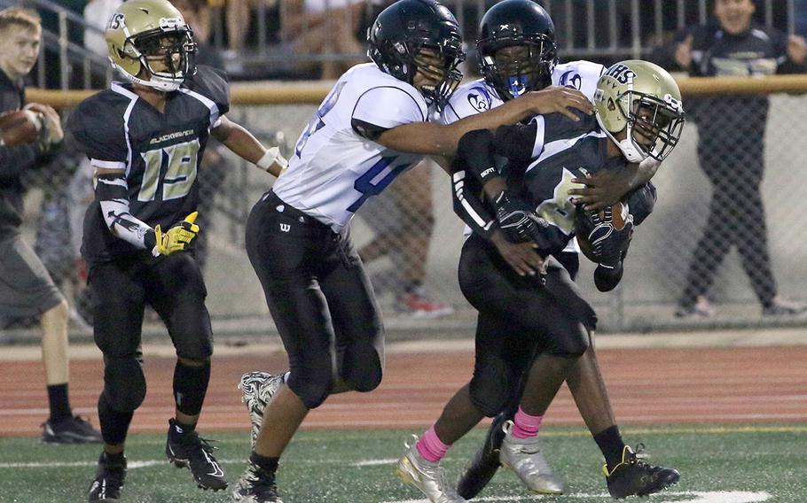 Humphreys Black's Tyler Wilks tries to shake off the tackle of Osan's Damon Turner and Gavin Lunn.