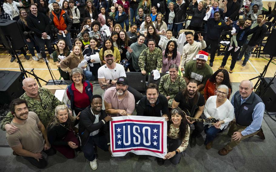 U.S. Navy Adm. Christopher Grady, Vice Chairman of the Joint Chiefs of Staff and an ensemble of celebrities traveling as part of the USO tour pose for a photo