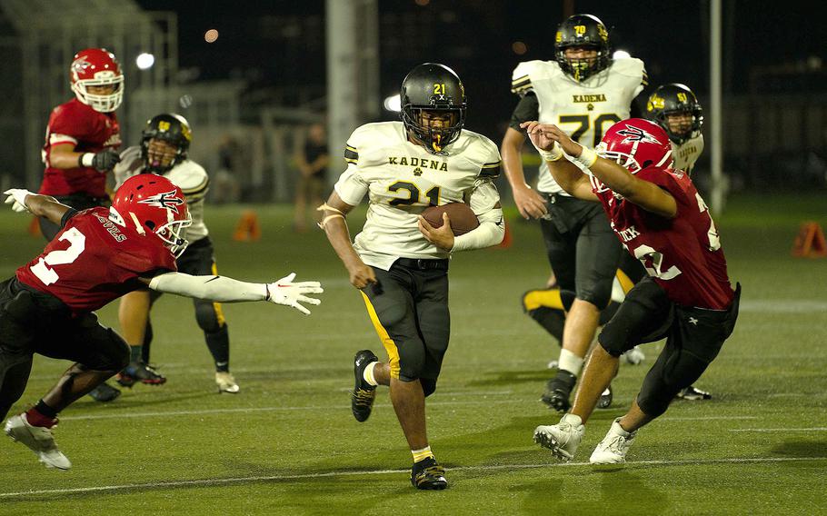 Kadena's D'Kylan Woods knifes his way through Nile C. Kinnick defenders Xavier Wright and Jacob Gilbrech. 