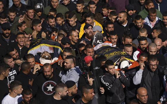 Palestinian mourners carry the bodies of Naeem Jamal Zubaidi, 27, right and Mohammad Ayman Saadi, 26, covered with flags of the Islamic Jihad Movement, during their funeral in the West Bank city of Jenin, Thursday, Dec. 1, 2022. Israeli forces killed Zubaidi and Saadi during an arrest raid Thursday in the occupied West Bank, according to the Israeli military and the Islamic Jihad militant group, the latest bloodshed in months of violence between the sides. (AP Photo/Nasser Nasser)