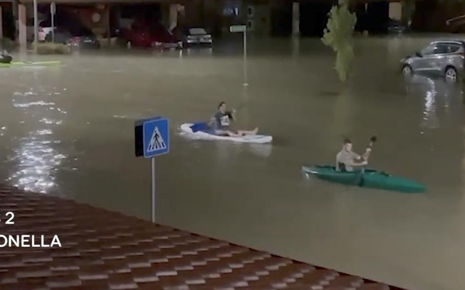In a still image from an eyewitness video, a paddleboard and kayakers float through the flooded housing complex at Naval Air Station Sigonella, Italy, recently after heavy rains hit Sicily.