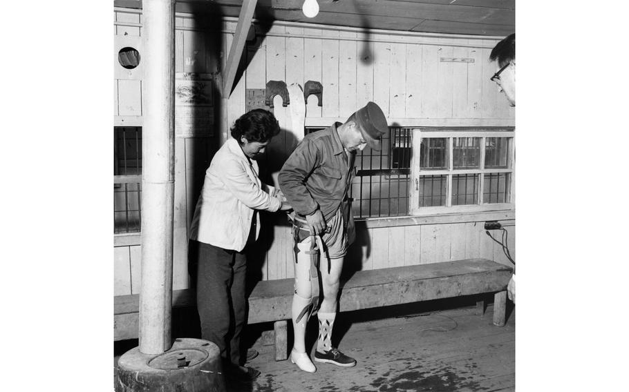 A new artificial leg is fitted to a disabled veteran of the Korean War by Dr. Chung Hie Oh at the National Rehabilitation Center in Pusan [Busan]. After the veteran has become accustomed to wearing, and walking with, the new leg, he will be enrolled in a trade school.