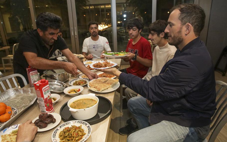 Colin Hannigan, left, who served in the Marine Corps and helped Maqsoud’s family escape Afghanistan, joins other Afghan refugees as they break their first day of Ramadan fasting at a local hotel on Saturday, April 2, 2022, in San Diego, Calif.