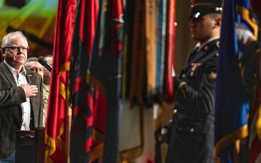 Minnesota Gov. Tim Walz, left, stands at attention for the posting of the flag during deployment ceremonies for 550 members of the Minnesota National Guards 34th Infantry Division Red Bulls at Grace Church on Thursday, Feb. 2, 2024, in Eden Prairie, Minn.