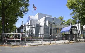 A white building seen behind a tall gated fence.
