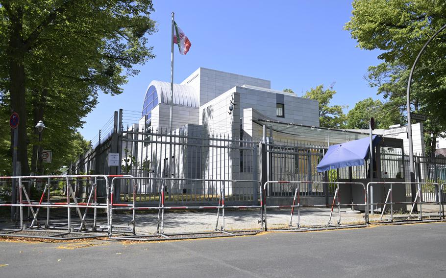 A white building seen behind a tall gated fence.