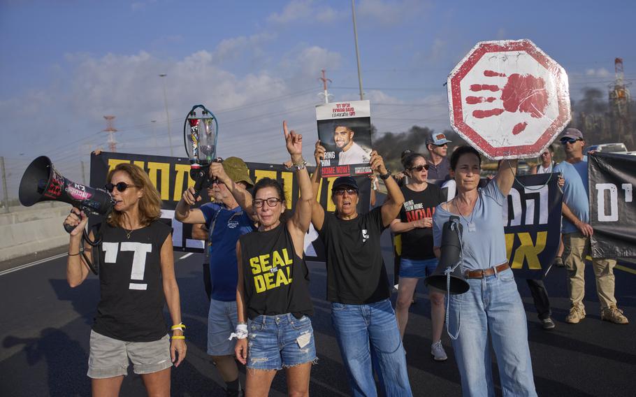 Activists in t-shirts hold signs and bullhorns on a highway.