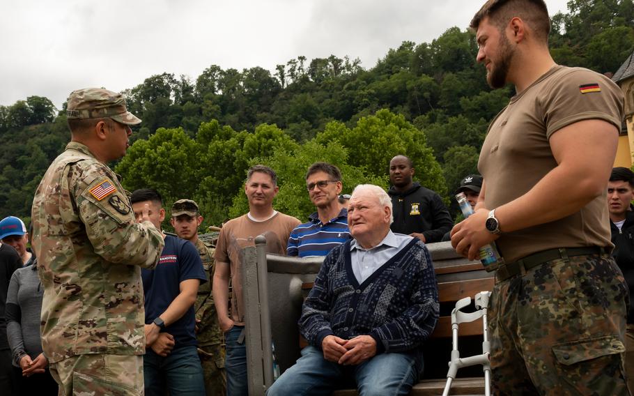 Army Lt. Col. Raul Sandoval, adjutant general of the 21st Theater Sustainment Command, left, presents a commander’s coin to Kurt Mebus at a ceremony in St. Goar, Germany, on July 11, 2022. Mebus was shot during World War II when he was 11 years old, which resulted in him losing a leg. 
