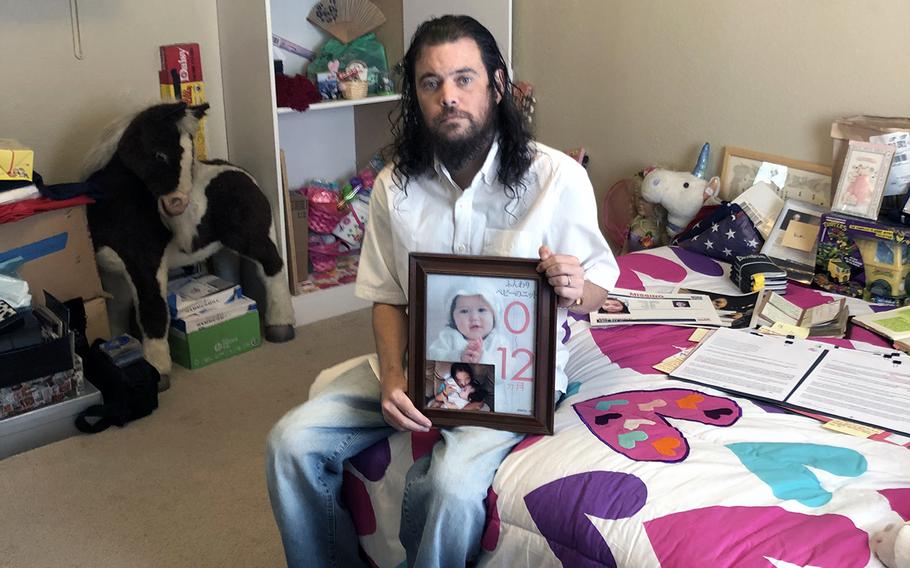 Donny Conway, a former Navy petty officer second class, poses with photos of his daughters, Christina and Chihiro, at his California home on Oct. 17, 2022.