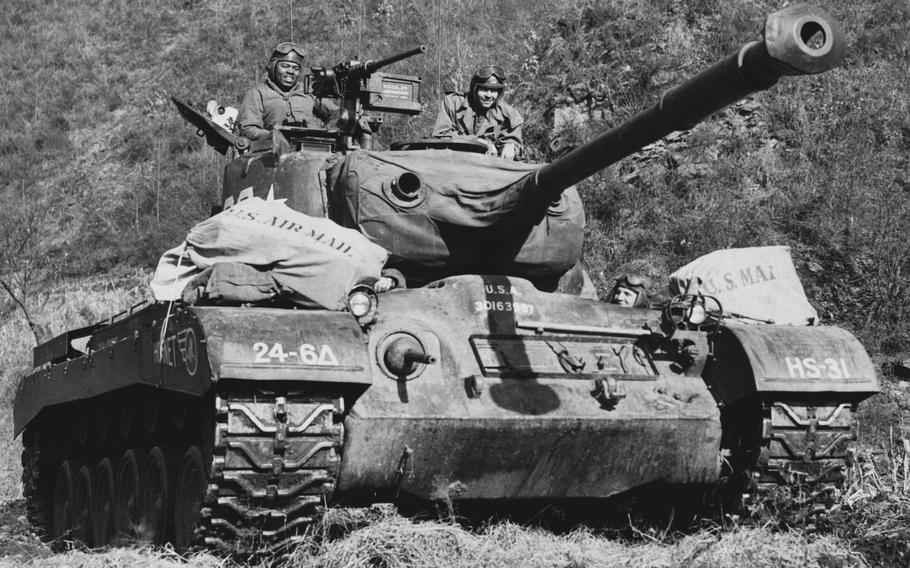 Service members transport bags of mail on a tank.