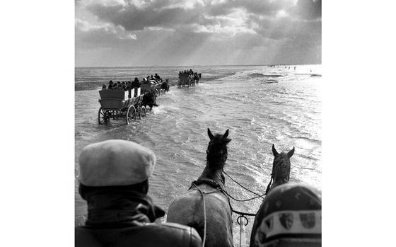 Duhnen, West Germany, May, 1960: A seagoing wagon train heads across shallow water for the island of Neuwerk, about six miles out to sea in northwestern Germany. When the tide of the so-called Wadden Sea was low enough for the markers showing the route (upper right) to be visible, trains of up to 37 wagons would carry tourists on the hour-long trek to the small island, population - then - 70. One can still reach the island this way now. 

Want to know what other interesting places to visit in Germany this summer? Check out Stars and Stripes' Europe community site.
https://europe.stripes.com/travel/

META TAGS: Germany; history; German culture; way of life; travel; summer