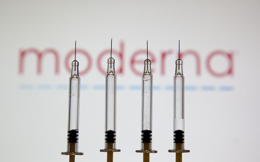 Medical syringes are seen displayed in front of the logo of pharmaceutical giant Moderna. 