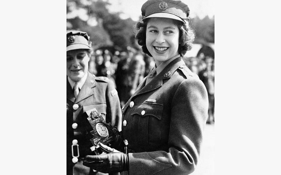 Britain’s Then-Princess Elizabeth, a Junior Commander in the Auxiliary Territorial Service, receives a clock presented to her by her old associates at the camp where she received her early training, during a ceremony at the No. 1 M.T. Training Center, in Camberley, England, Aug. 3, 1945. 