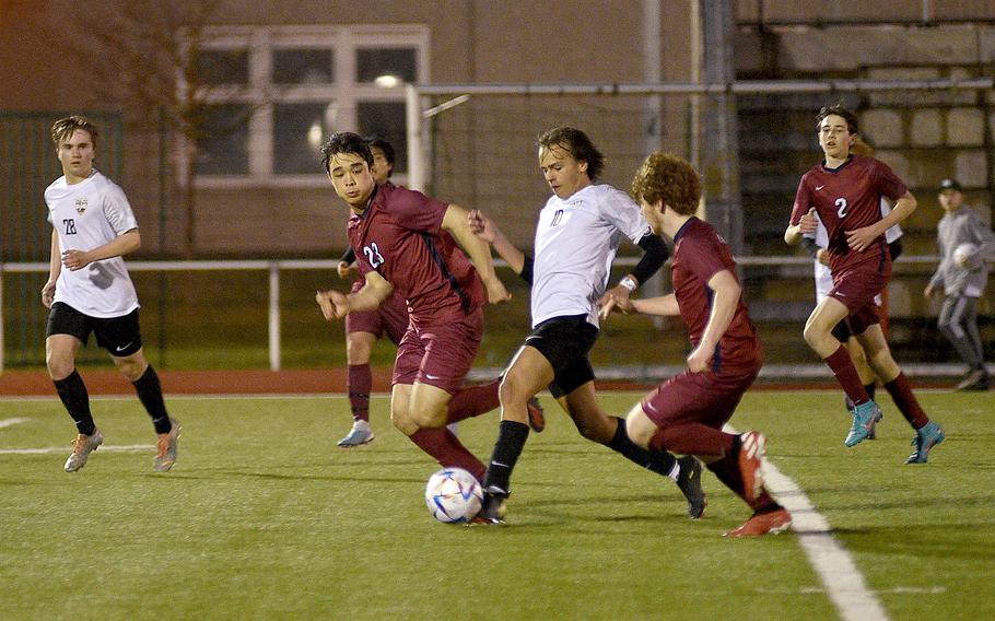 Stuttgart's Ryan Stevenson tries to dribble through Lakenheath defender Ryuu Flynn, center left, and midfielder Joshua Gabel, center right, on Friday evening at Kaiserslautern High School in Kaiserslautern, Germany.