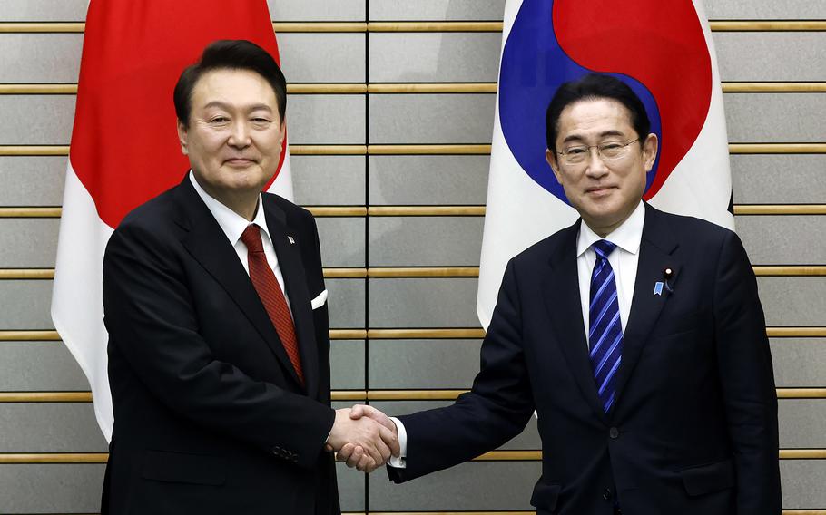 South Korean President Yoon Suk Yeol, left, and Japanese Prime Minister Fumio Kishida, right, shake hands, ahead of their bilateral meeting at the Prime Minister's Office, in Tokyo, Japan, Thursday, March 16, 2023.