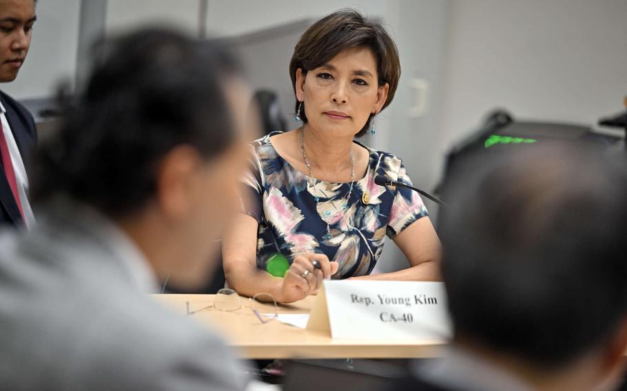 A woman sits a table and looks across at a man