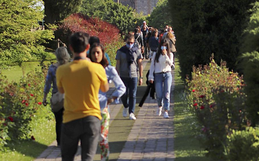 Visitors walk along a path with a view of the Scaligero Castle in Villafranca di Verona, from the Avenue of the Roses, inside the Garden Park Sigurta. 