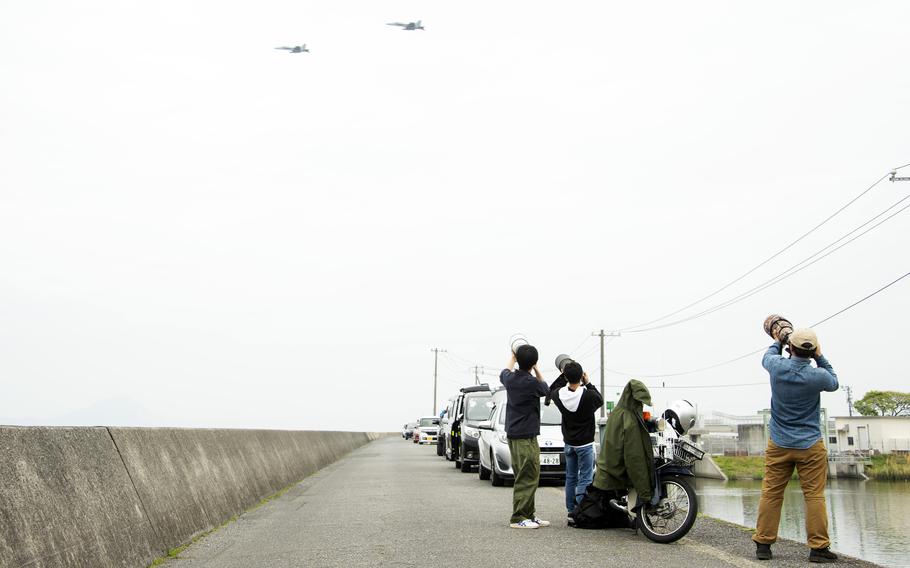 Onishi Hiroki, left, Masafumi Mizuoka, center, and Taiki Kuwabara take photos of U.S. Navy F/A-18 Hornets taking off from Marine Corps Air Station Iwakuni, Japan, April 19, 2023.