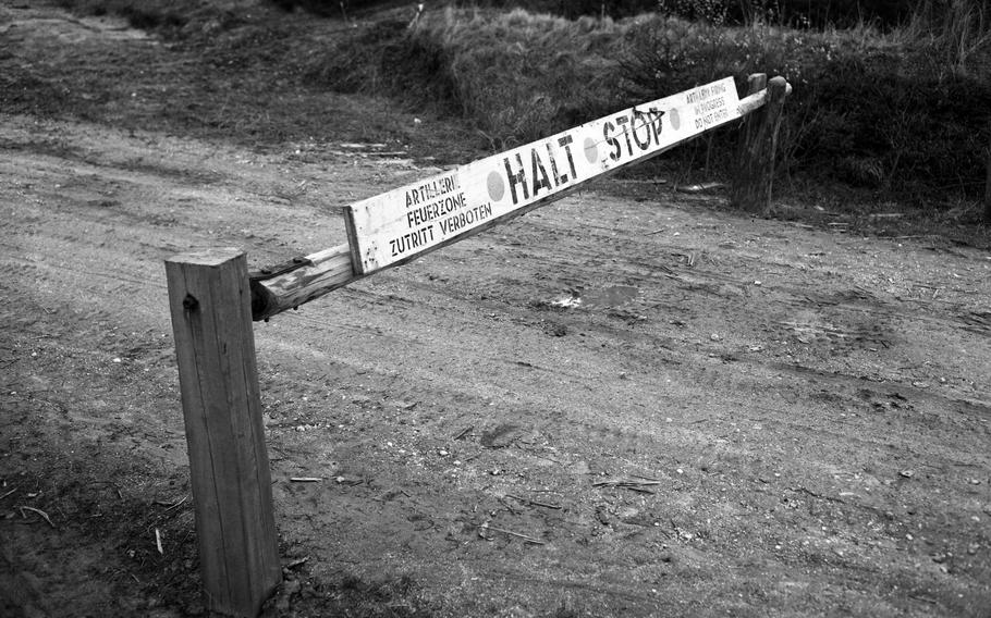 A photo of a barrier arm that reads “HALT” and “STOP” in English, among other things.