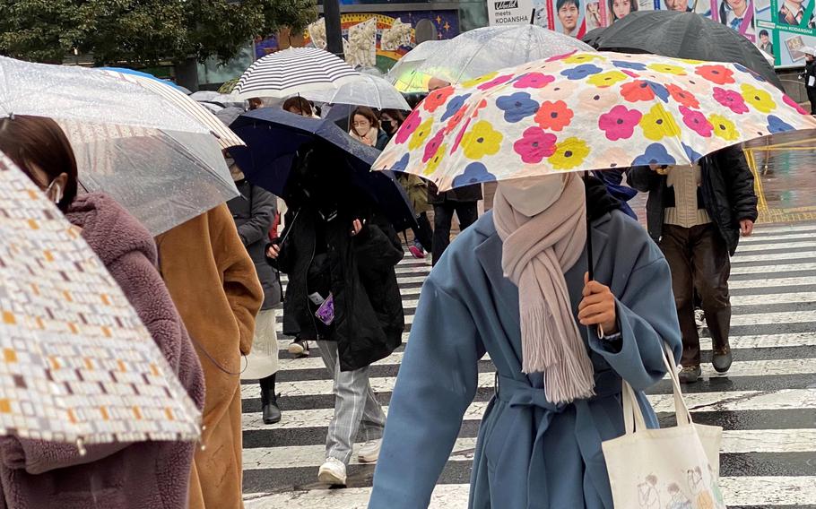 Pedestrians rush across the busy Shibuya Scramble intersection in central Tokyo, Sunday, Feb. 13, 2022. 