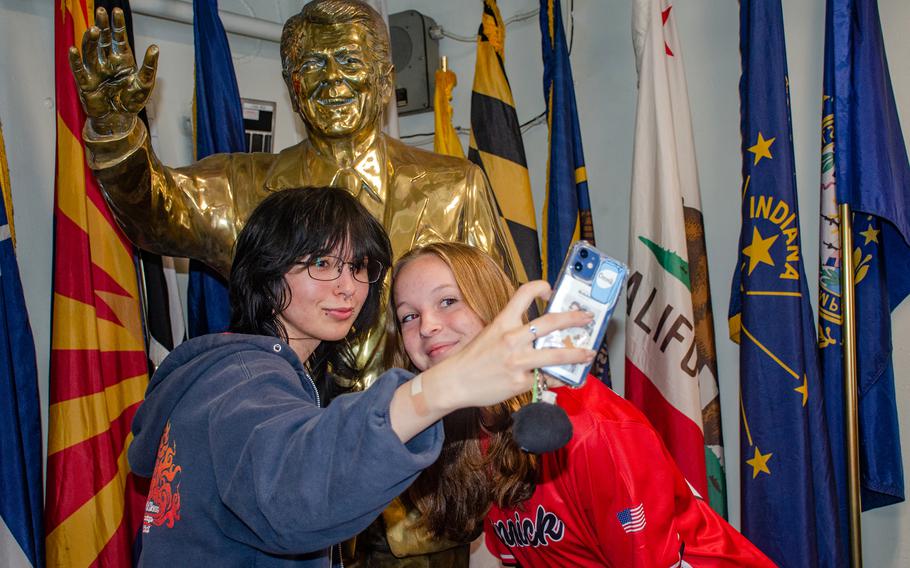 Seniors from Nile C. Kinnick Senior High School take a selfie with a statue of Ronald Reagan aboard the former president's namesake aircraft carrier at Yokosuka Naval Base, Japan, April 18, 2023.