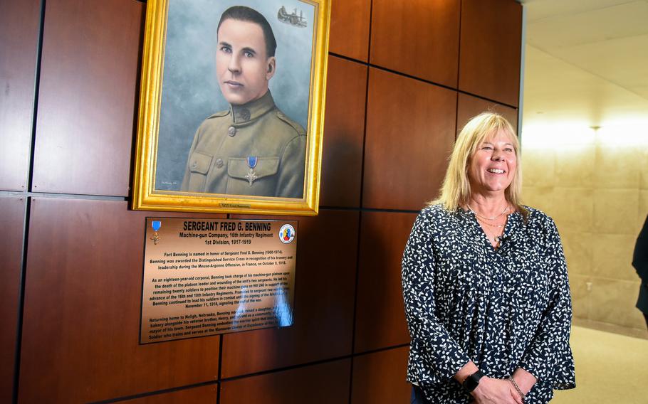A woman stands next to a painting.