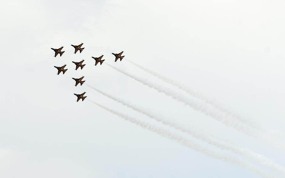 Eight military fighter jets, seen from below, fly in formation during an air show.
