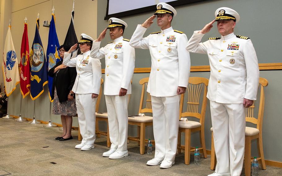 Navy officers salute during a change-of-command ceremony