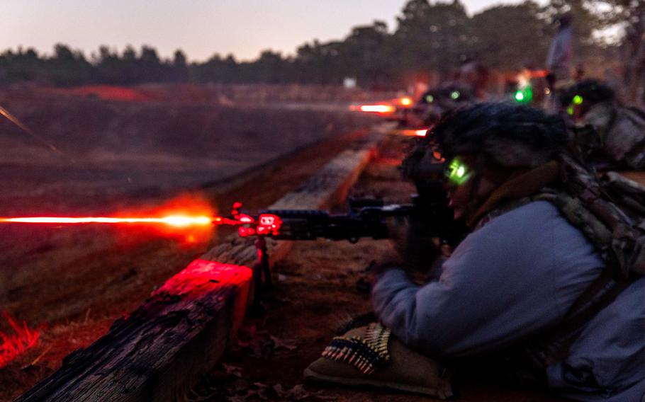 Soldiers fire machine guns in near-darkness.