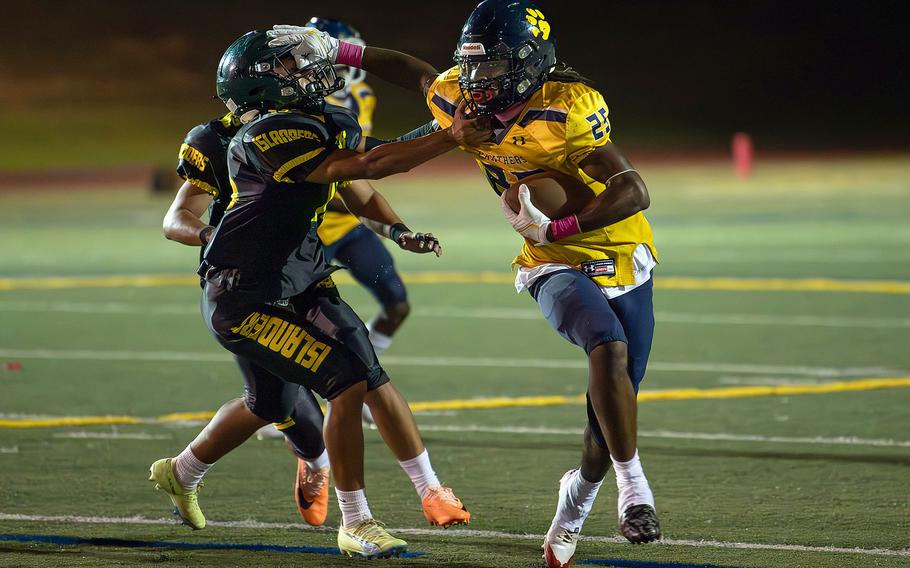 Guam High's Cameron Brantley gives the stiff arm to John F. Kennedy's defense.