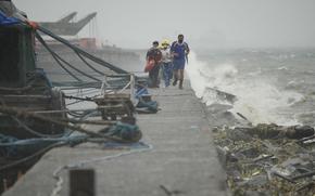 Rescuers run as they check residents living at the seaside slum district of Tondo while Typhoon Noru approaches Manila, Philippines, Sunday, Sept. 25, 2022.