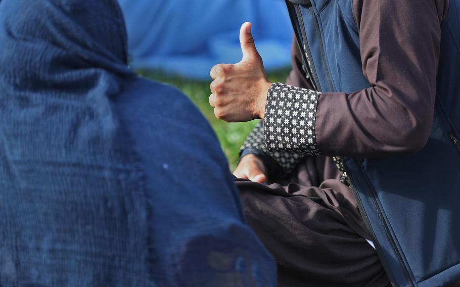 An Operation Allies Welcome evacuee gives a thumbs up to touring members of the media, as he sits outside one of services buildings Thursday, Oct. 14, 2021, at Camp Atterbury in Edinburgh, Ind.